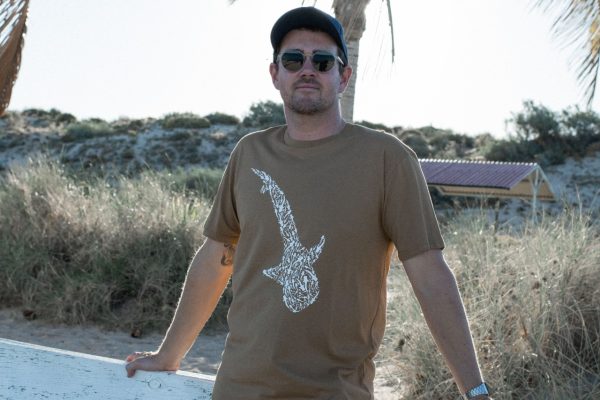 A man in sunglasses is wearing an olive green t-shirt with a white whale shark print.