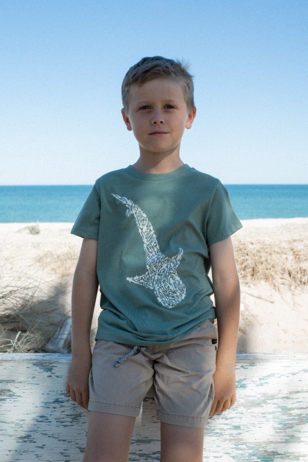 The same child from the previous image, now facing forward, wearing a blue T-shirt with a white whale shark design on the front.