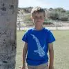 The same child from the previous image, now facing forward, wearing a blue T-shirt with a white whale shark design on the front.