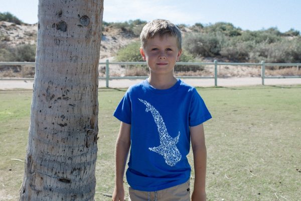 The same child from the previous image, now facing forward, wearing a blue T-shirt with a white whale shark design on the front.